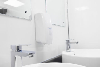 Photo of public washroom sinks with soap dispenser.